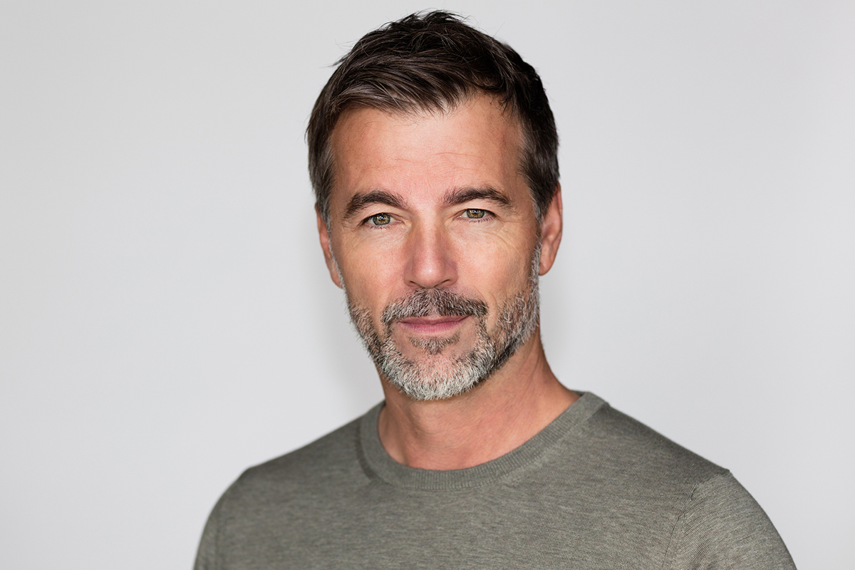 a middle aged man with a beard looks at the camera looking content after hormone replacement therapy in Bellevue