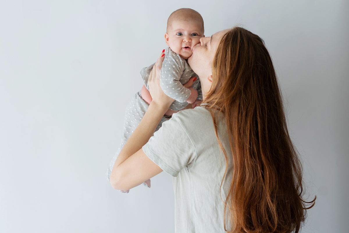 a woman holding a baby and kissing them on the cheek after the woman got ThermiVa in Bellevue